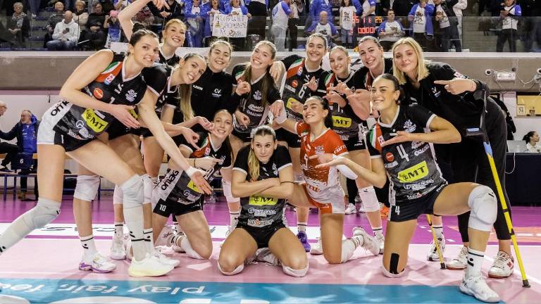 La Omag-Mt, compresa l’infortunata Giulia Polesello, festeggia la vittoria nel derby con la Clai Imola, a destra Katarina Bulovic contro il muro a due di Claudia Consoli e Cecilia Nicolini (Masini)