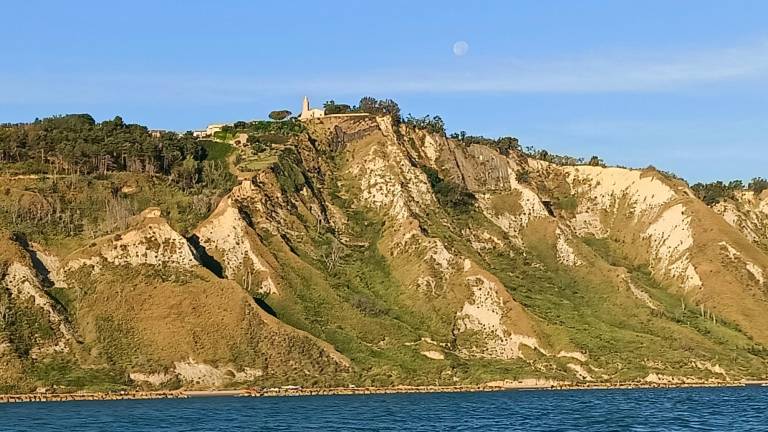 Il borgo di Fiorenzuola con la chiesa visto dal mare all’alba quando ancora si intravede la luna